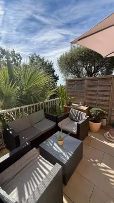 a patio with couches and tables and an umbrella at Modern apartment with sunny terrace in Nice