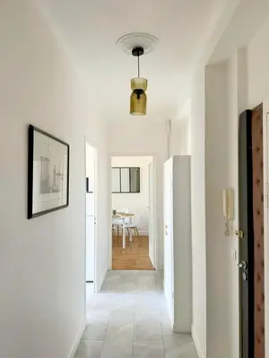 a hallway with white walls and a door with a table at Charmant appartement avec balcon, près de la plage et Promenade des Anglais in Nice