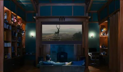 a man sitting on a couch in a room with a big screen at Appartement Haut Standing coeur de Nice pour 6pers in Nice