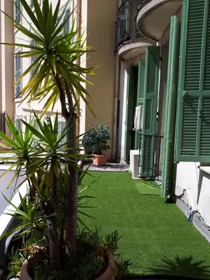 a courtyard with palm trees in a building with green shutters at Appartements Massena in Nice