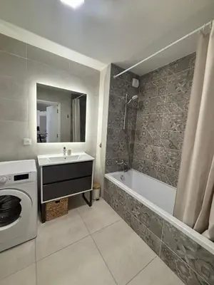 a bathroom with a tub and a sink and a washing machine at L'Odyssée in Saint-Laurent-du-Var