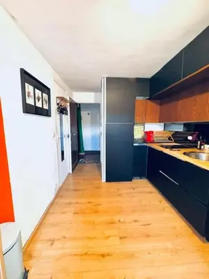 a kitchen with a wooden floor and black cabinets at Cosy studio au Coeur du Centre Ville in Nice