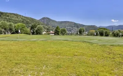 a green golf course with mountains in the background at Le 120 m2 - luxe, piscine, terrasse et garage in Nice