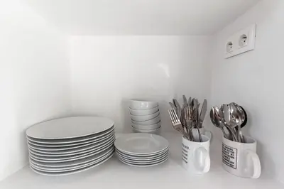a pile of plates and utensils sitting on a shelf at Le Garibaldi - City centre - Bright - AC in Nice