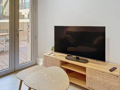 a living room with a flat screen tv on a wooden stand at Charmant 2P neuf avec terrasse, proche mer in Nice