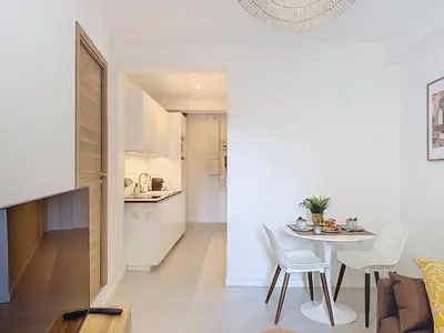 a white kitchen and dining room with a table and chairs at Charmant 2P neuf avec terrasse, proche mer in Nice
