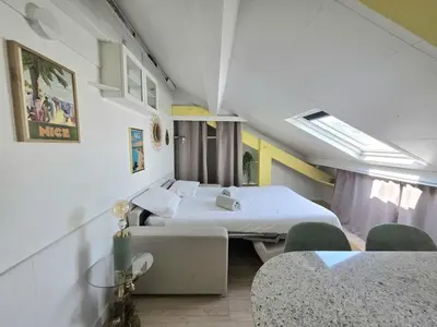 a room with two beds and a table and chairs at Cosy sous les toits - Nice Gare - 2 pers in Nice