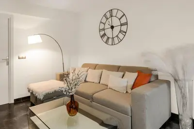 a living room with a couch and a clock on the wall at Havre de Paix Mont Boron Proche du Port in Nice