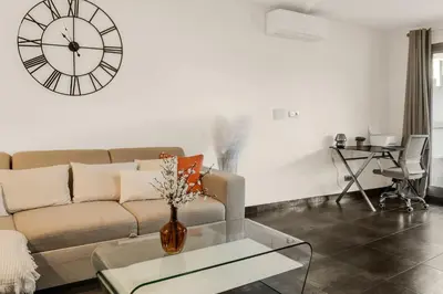 a living room with a couch and a clock on the wall at Havre de Paix Mont Boron Proche du Port in Nice
