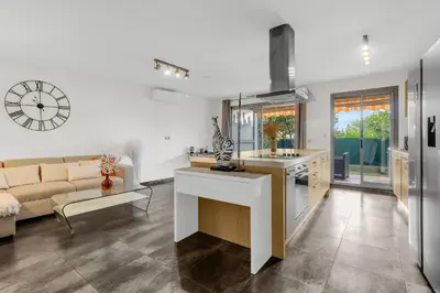 a kitchen and living room with a clock on the wall at Havre de Paix Mont Boron Proche du Port in Nice