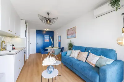 a living room with a blue couch and a kitchen at Nice Renting - CARNOT - Escape to French Riviera Terrace with Sea View in Nice