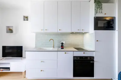 a kitchen with white cabinets and a sink and a stove at Nice Renting - CARNOT - Escape to French Riviera Terrace with Sea View in Nice