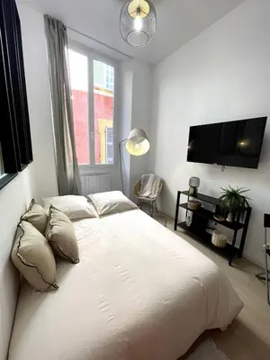 a bedroom with a large white bed and a tv at Studio Vieux-Nice proche de la mer et Cours Saleya in Nice