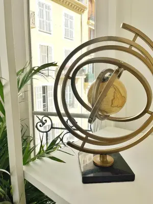 a metal clock on a table next to a window at Studio sur la promenade des anglais in Nice