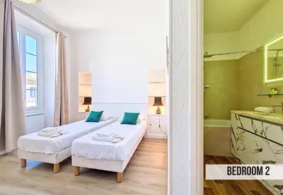 a bedroom with two beds and a bathroom with a tub at Nestor&Jeeves - BLEU PANORAMA - Vue Mer exceptionnelle in Nice