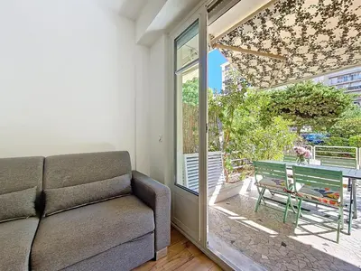 a living room with a couch and a sliding glass door at Nestor&Jeeves - MANEL - Terrasse et acces direct Promenade des Anglais in Nice