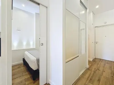 a bedroom with white walls and a bed and a mirror at Nestor&Jeeves - MANEL - Terrasse et acces direct Promenade des Anglais in Nice