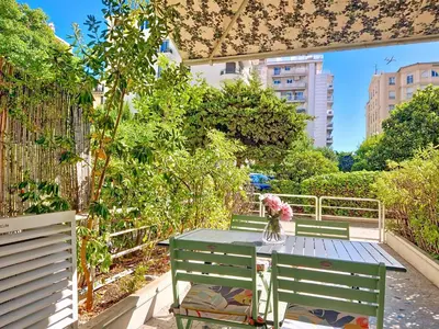 a table with a vase on top of it next to two benches at Nestor&Jeeves - MANEL - Terrasse et acces direct Promenade des Anglais in Nice