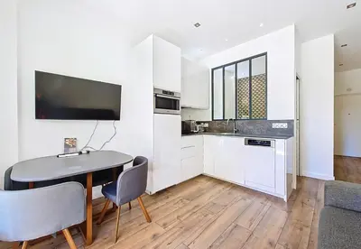 a kitchen with white cabinets and a table and chairs at Nestor&Jeeves - MANEL - Terrasse et acces direct Promenade des Anglais in Nice