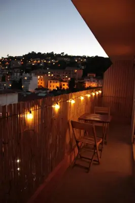 a table and chairs on a balcony with lights at Le Cocon Niçois Studio Cozy et Lumineux avec Parking in Nice