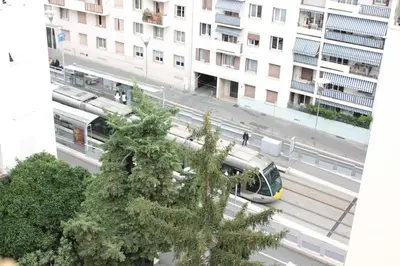 a train on a city street with buildings at Le Cocon Niçois Studio Cozy et Lumineux avec Parking in Nice