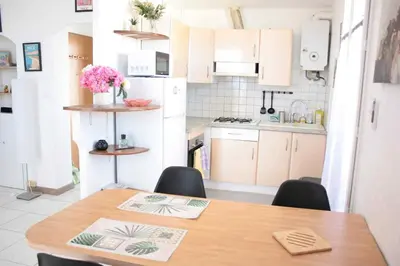 a kitchen with a wooden table and chairs in it at Le Cocon Niçois Studio Cozy et Lumineux avec Parking in Nice