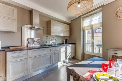 a kitchen with wooden cabinets and a table with a dining room at VUE MAGENTA AP4484 by Riviera Holiday Homes in Nice