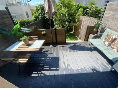 a patio with an umbrella and a table and a couch at Apartsuite jardin Nice cap 3000 bord de mer in Saint-Laurent-du-Var