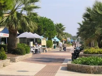 a street with palm trees and people sitting at tables at Apartsuite jardin Nice cap 3000 bord de mer in Saint-Laurent-du-Var