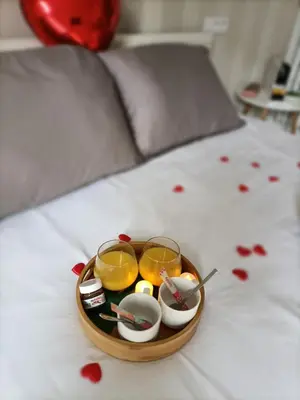 a tray of food with two glasses on a bed at Apartsuite jardin Nice cap 3000 bord de mer in Saint-Laurent-du-Var
