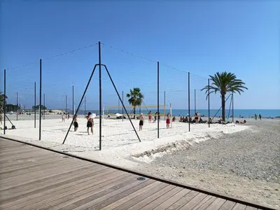 a volleyball net on a beach with people playing at Apartsuite jardin Nice cap 3000 bord de mer in Saint-Laurent-du-Var