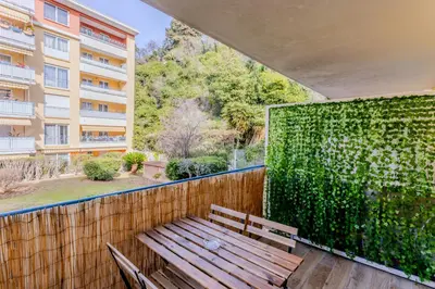 a wooden bench on a balcony with a green wall at Peaceful apartment in Nice with terrace, parking in Nice