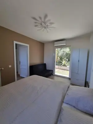a bedroom with a bed and a ceiling fan at 2 pièces avec jardin vue mer in Saint-Laurent-du-Var