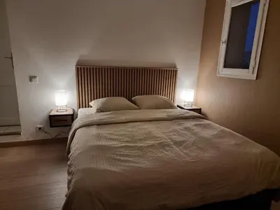 a bedroom with a large bed with two lamps on both sides at 2 pièces avec jardin vue mer in Saint-Laurent-du-Var