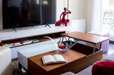 a living room with a tv and a table with books at Appartement luxueux entier 3 chambres in Nice