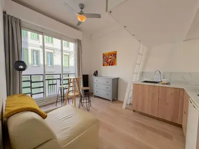 a living room with a couch and a kitchen with a table at ⁂ Petit nid design au centre de Nice in Nice