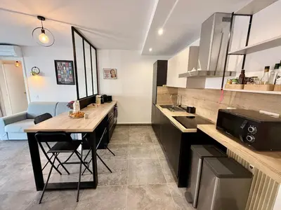 a kitchen with a table and a counter top at Spacieux 3 pièces Gambetta, proche Tramway in Nice