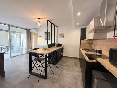 a kitchen with a table and a counter top at Spacieux 3 pièces Gambetta, proche Tramway in Nice
