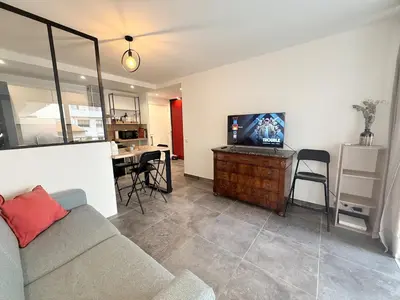 a living room with a couch and a tv and a table at Spacieux 3 pièces Gambetta, proche Tramway in Nice