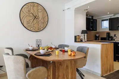 a kitchen with a wooden table and a clock on the wall at MY CASA - PALAIS MED 702 D - 2 bedroom Down Town with Terasse AC in Nice