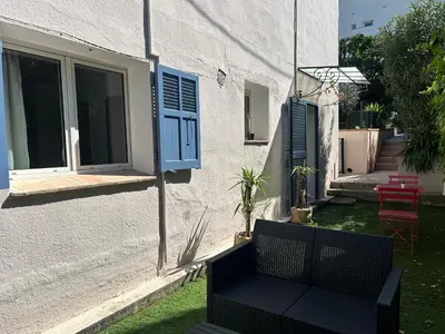 a yard with chairs and a table and a building at Two rooms with 30 m2 garden in villa in Cagnes-sur-Mer