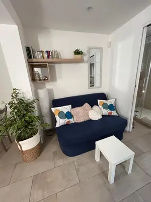 a living room with a blue couch and a table at Two rooms with 30 m2 garden in villa in Cagnes-sur-Mer