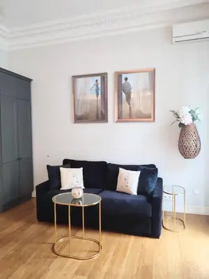 a living room with a black couch and two tables at Studio in the heart of Nice close to amenities in Nice