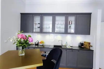a kitchen with black cabinets and a table with a vase of flowers at Studio in the heart of Nice close to amenities in Nice