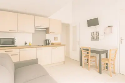 a kitchen with white cabinets and a table and chairs at Le Carré D'or 2 Pers Centrale WiFi AC in Nice