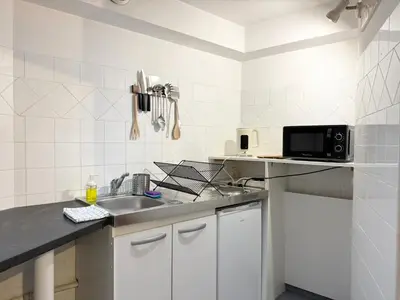 a white kitchen with a sink and a microwave at Appartement à 100 m de la mer avec stationnement gratuit in Nice