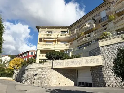 a large white building with a stone wall at Appartement à 100 m de la mer avec stationnement gratuit in Nice
