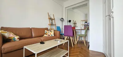 a living room with a brown couch and a table at Le grand Escurial in Nice