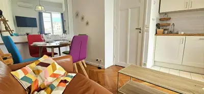 a living room with a couch and a table and a kitchen at Le grand Escurial in Nice