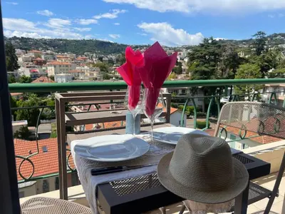 a table with a hat and a vase with flowers on a balcony at Apartment nice view in Nice